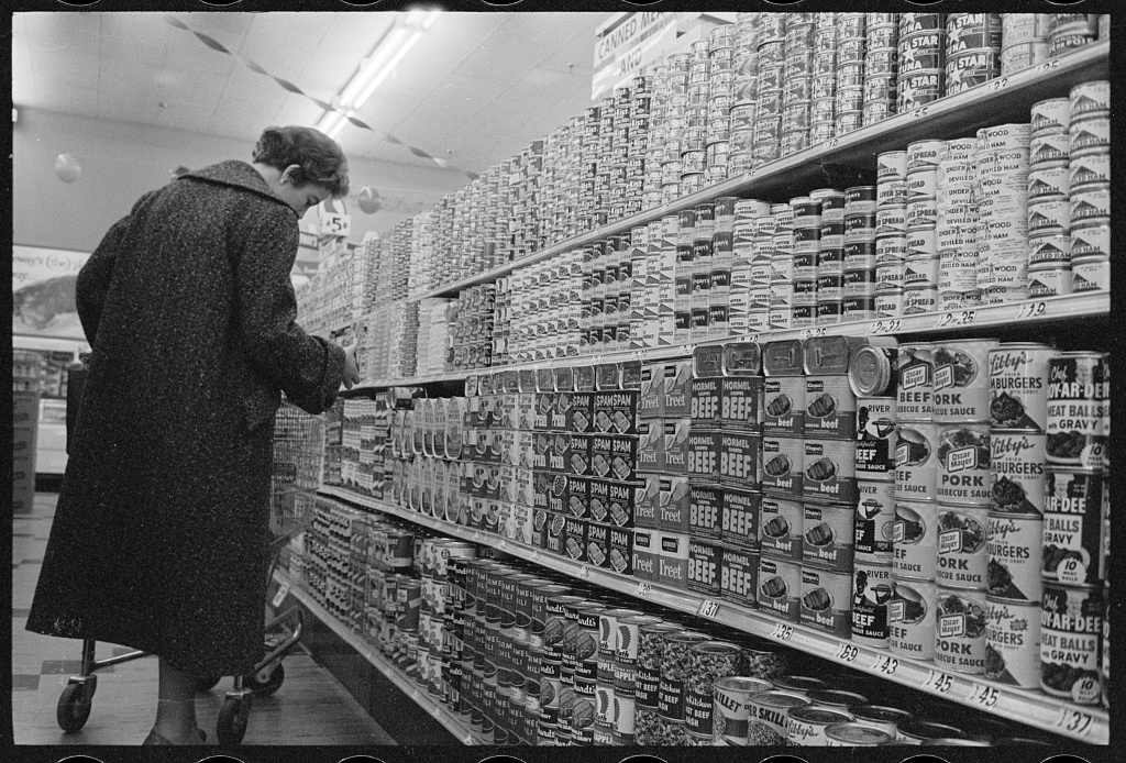 A shopper standing beside canned goods in a supermarket in 1957